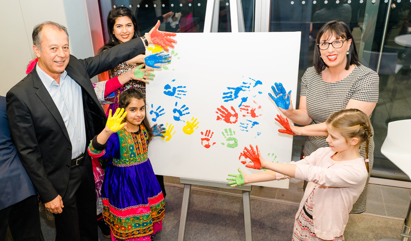 Staffelei mit Bild, auf dem farbige Handabdrücke zu sehen sind, Kinder und Erwachsene (Naim Ziayee, Sarina Ziayee, Karin-Brigitte Göbel).